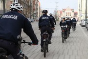 grupa umundurowanych policyjnych cyklistów jedzie po ulicy Poznania - ujęcie od tyłu