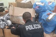 Zdjęcie przedstawia policjanta odwróconego plecami, który wyciąga z kartonów odzież.