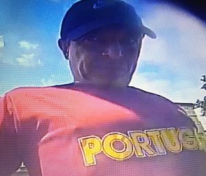 wizerunek mężczyzny podejrzewanego o oszustwo. Mężczyzna ubrany jest w koszulkę typu t-shirt w kolorze pomarańczowym oraz czapkę z daszkiem w kolorze czarnym