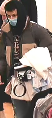 kobieta ubrana w beżową zimową  czapkę z pomponem, beżową zimową, puchową kurtkę, czarne spodnie, buty za kostkę w kolorze beżowym, małą beżową torebkę przewieszoną przez ramię, a na twarzy ma maseczkę zasłaniającą usta i nos. Mężczyzna ubrany w czarną bluzę z kapturem na głowie, maseczkę zasłaniającą usta i nos, spodnie - dżinsy niebieskie, kurtkę puchową w kolorze brązowym i czarny plecach przewieszony na plecach