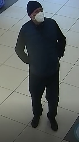 mężczyzna w wieku około 45 lat, normalnej budowy ciała, ubrany w czarną, zimową czapkę, granatowy pikowany bezrękawnik, ciemną bluzę oraz spodnie, na twarzy ma maseczkę zasłaniająca usta i nos