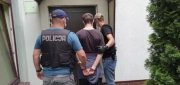 mężczyzna w asyście dwóch policjantów jest prowadzony do komisariatu policji na północy, ma założone kajdanki na ręce trzymane z tyłu.