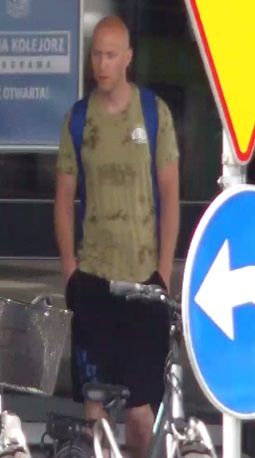 mężczyzna wysoki, szczupły, około 35-40 lat, ubrany w koszulkę tshirt z krótkim rękawem oraz dresowe krótkie spodnie, na plecach ma założony niebieski plecak