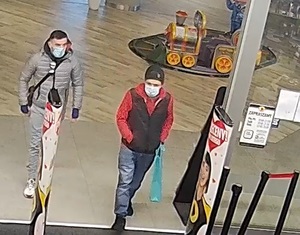 1 z mężczyzn ubrany w dżinsy, czarne, sportowe buty, czerwoną bluzę z kapturem, czarny bezrękawnik, w lewej ręce trzyma torbę od prezentu, ręce ma schowane w kieszeni od spodni, na twarzy maseczkę zasłaniającą usta i nos, a na głowie czarną, zimową zimową
2 mężczyzna ma białe, sportowe buty, jasne dżinsy,  pikowaną szarą kurtkę z kapturem, czarne rękawiczki, torbę przewieszoną przez ramię, maseczkę na twarzy zasłaniającą usta i nos, czarne włosy przeczesane na jeden bok